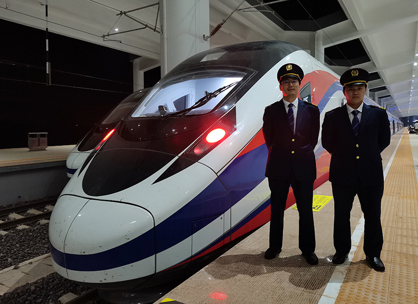 劉銀能（右一）與中國(guó)師父鄔俊鴻在動(dòng)車(chē)組前合影。受訪者供圖